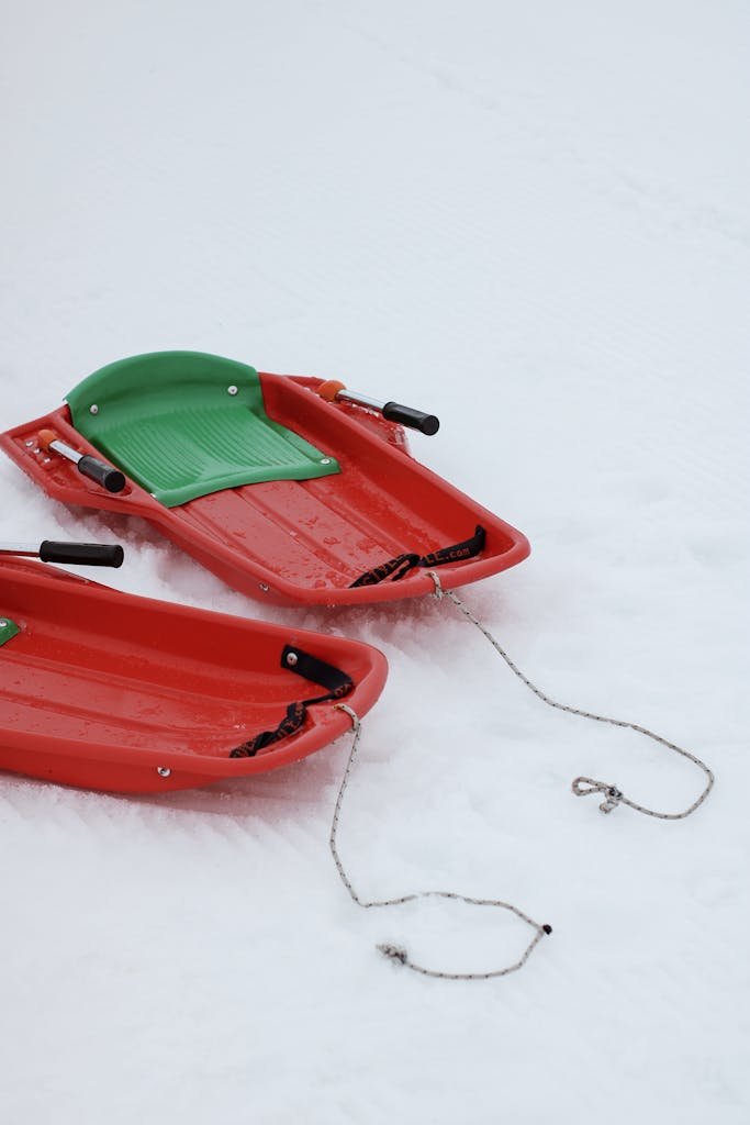 Vibrant red sleds resting on untouched snow, evoking a playful winter scene.